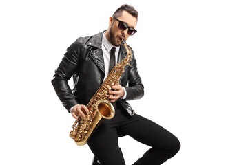 Male musician in a leather jacket sitting and playing a saxophone - obrazy, fototapety, plakaty