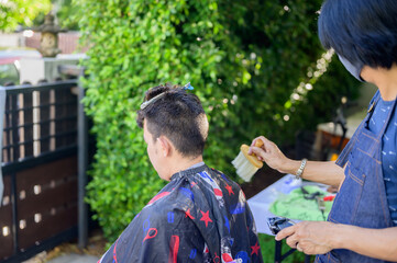 Asian businessman making haircut at home garden. Social distancing and New normal lifestyle.