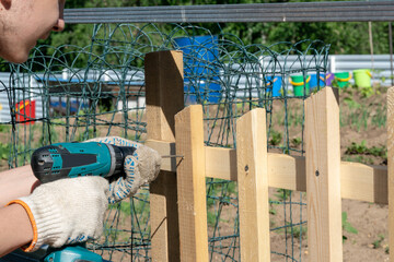 Building a wooden fence with a screwdriver. Natural eco-friendly materials for construction and...
