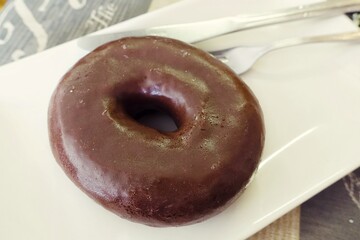Appetizing donut with chocolate icing on a plate