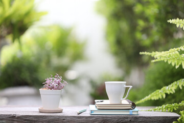 white cup with notebooks and pencil with small purple plant pot on wooden table view