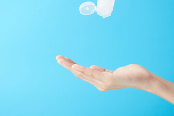 Close up woman hands using wash hand sanitizer gel in blue background.