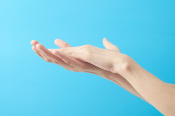 Close up woman hands using wash hand sanitizer gel in blue background.