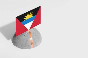 Antigua and Barbuda flag tagged on rounded stone. White isolated background. Side view minimal national concept.