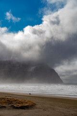 People wanking on the beach at Seaside, Oregon, Tillamook head in background.
