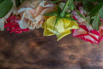 Multicolored bouquet of fresh roses on a wooden background. Beautiful flowers.