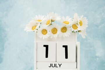 White cube calendar for july decorated with daisy flowers