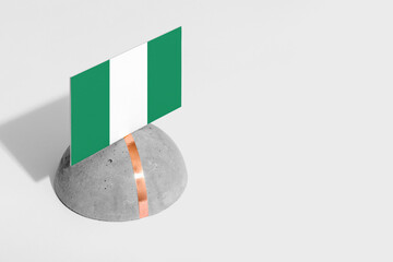 Nigeria flag tagged on rounded stone. White isolated background. Side view minimal national concept.