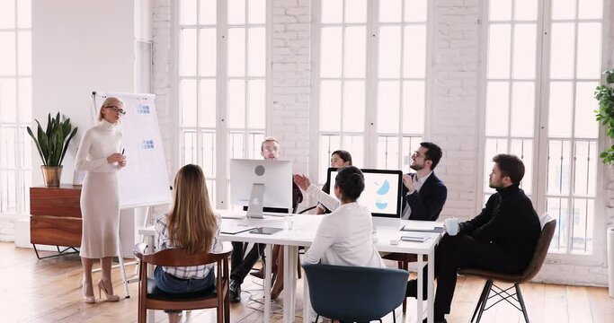 Full length concentrated skilled young female speaker answering questions after finishing educational seminar. Smart team leader or business coach trainer explaining company development strategy.