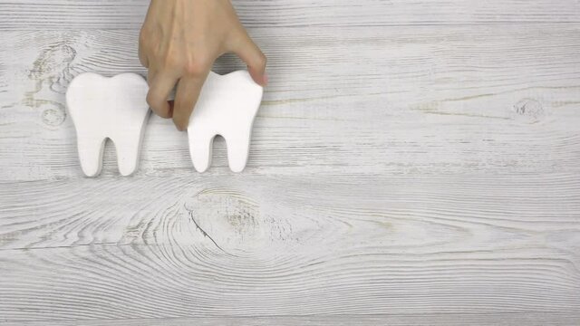 Female hand puts teeth and a pink piggy bank on a wooden table. Investing in dental health care.