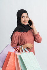 muslim young shopping woman make a phone call while holding a paper bag