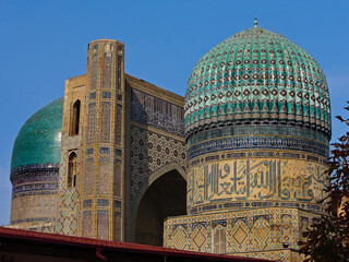 Portal and one of buildings of famous cathedral Mosque of Bibi Khanym, one of popular tourist sights in Samarkand, Uzbekistan. All of buildings richly decorated with traditional eastern ornaments.