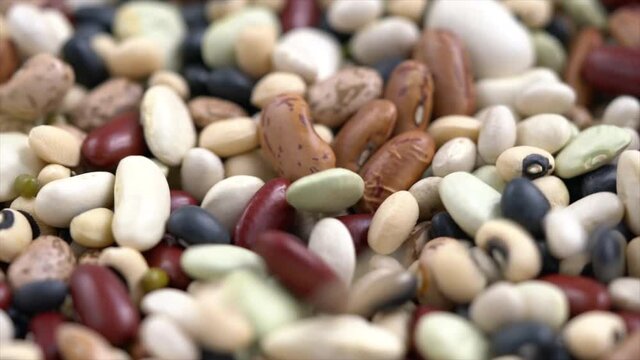 Close up a pile of mixed beans and there were some beans falling in the pile at the same time.