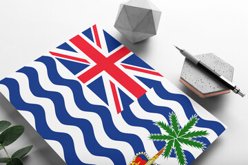 British Indian Ocean Territory flag on minimalist paper background. National invitation letter with stylish pen on stone. Communication concept.