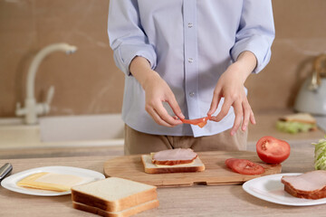 Boy is preparing breakfast for himself. Child is preparing a sandwich of bread.