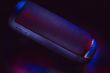 Clean black cylinder bluetooth speaker with black background and color lights. Product photo with...