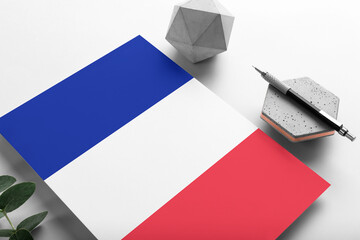 France flag on minimalist paper background. National invitation letter with stylish pen on stone. Communication concept.