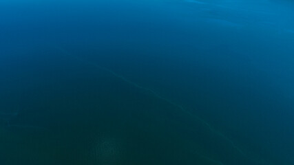 Aerial view of the blue waters of a lake in Italy. Sunlight is reflected on the surface of the water.