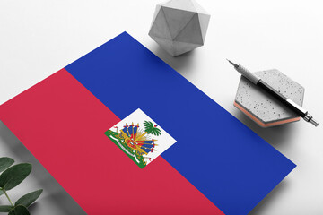 Haiti flag on minimalist paper background. National invitation letter with stylish pen on stone....