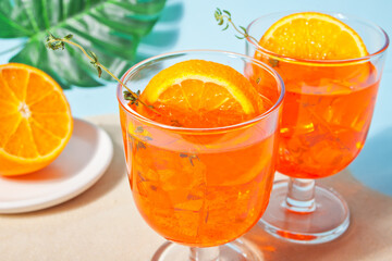 Glasses with fresh homemade orange sweet iced tea or cocktail, lemonade with thyme. Refreshing cold drink. Summer party.