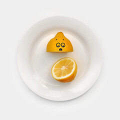 A sad lemon cut in half on a white plate. Conceptual image of the psychological state of loss of unity with oneself