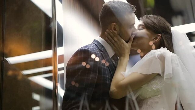 Wedding couple kisses in a beautiful and cozy elevator of the Kharkov Palace Hotel, Ukraine. Young happy bride and bearded groom secluded themselves in a comfortable elevator for hugs and kisses.