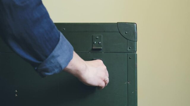 Man's Hands Close Green Military Storage Box for Ammunition. Green box from the War with Scratches and Locks in front.