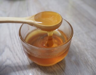 Selective focus,Honey is dripping from the wooden spoon  to the glass 