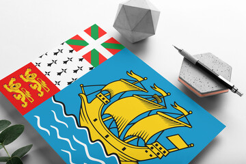 Saint Pierre And Miquelon flag on minimalist paper background. National invitation letter with stylish pen on stone. Communication concept.