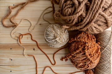 Knitting as a hobby. The yarn is beige, brown and light brown, knitting needles. Background of light wood. shades of brown on wood background