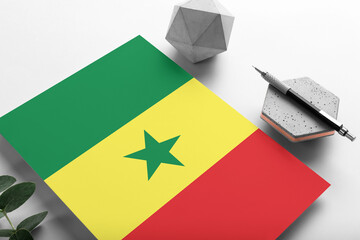 Senegal flag on minimalist paper background. National invitation letter with stylish pen on stone. Communication concept.