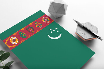 Turkmenistan flag on minimalist paper background. National invitation letter with stylish pen on stone. Communication concept.