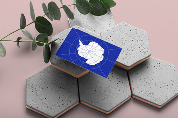 Antarctica flag on hexagon stylish stones. Pink copy space background. Flat lay, top view minimal national concept.