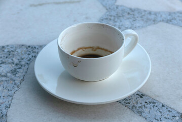 An empty white cup of coffee after drink on a marble background.