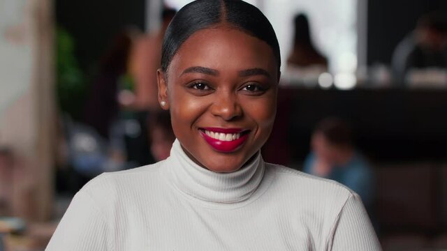 Portrait of happy young beautiful 20s gen-z black business woman with red lips smiling at camera at light trendy office.