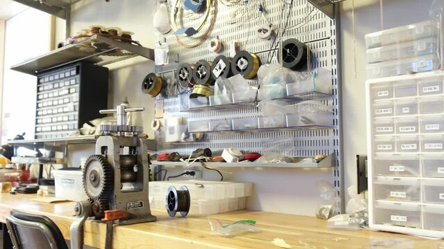 Shelves, desks and boxes full of jewelry tools and accessories. Panning video of jewelry accessories and boxes in the workshop.
