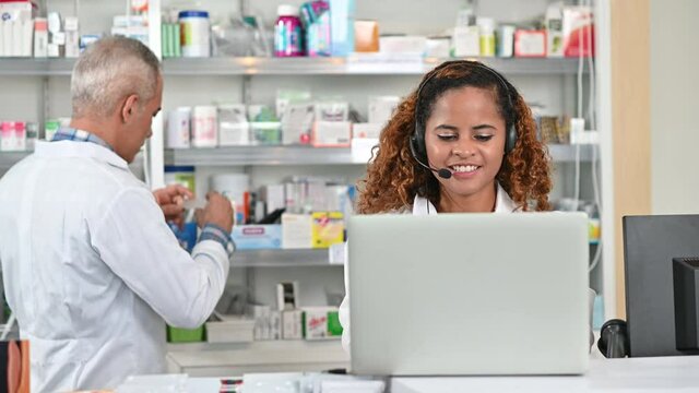 Young african american woman pharmicist working in drug store using laptop for receive online order