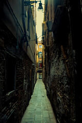 A dark and gloomy narrow alleyway with old buildings on either side