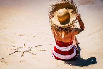Sun and summer holiday vacation concept with people at the beach and caucasian woman viewed from back with tourist hat enjoying the day and the outdoor relax leisure activity