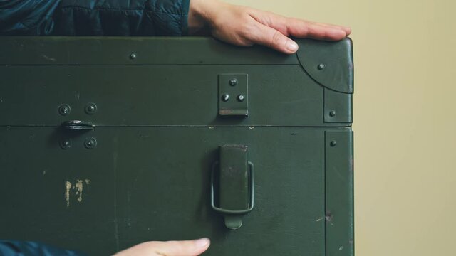 Woman's Hands Open Green Military Storage Box for Ammunition. Green box from the War with Scratches and Locks in front.