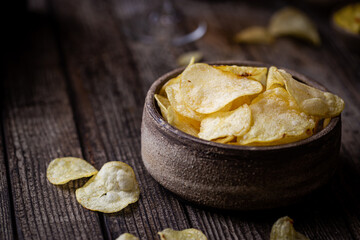 Crunchy delicious potato chips for a tasty snack break on dark rustic background