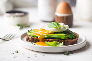 Healthy breakfast whole wheat toasted bread with avocado and poached egg over white background