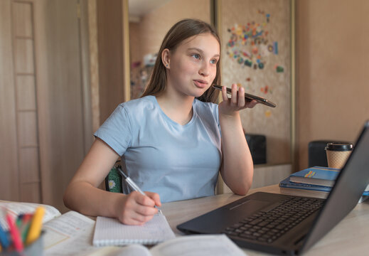 Teen girl doing homework, recording a voice message, making phone call, laptop monitor, e-education online lessons, distance learning. Social networks, watching a teacher&rsquo;s lecture on Internet.