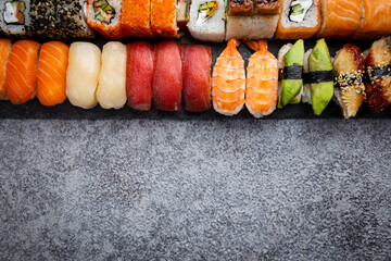 Set of sushi and maki with soy sauce over stone gray background. Top view with copy space