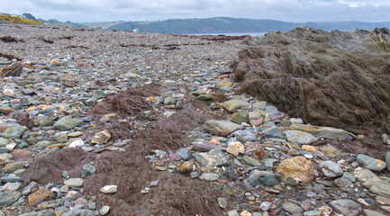 Fototapeta na wymiar Rocks, pebbles, rock pools, sandsand ocean on an overcast June day in Cornwall