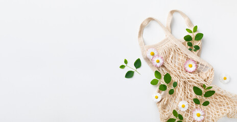 Natural and reusable cotton eco bag on green background top view. Zero waste and eco friendly concept for sustainable organic lifestyle. Flat lay.