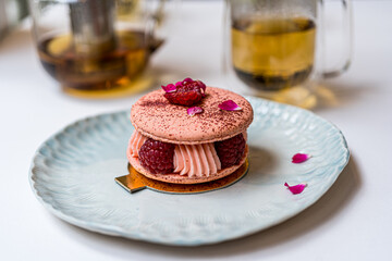 Pink Raspberry Macaron cookies on blue plate. Tea time. Blue table background. Top view. 