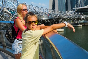 Traveling to Singapore,City of Future. Couple of caucasian child-travelers, brother and sister, in casual dress having fun together on family excursion urban tour. Helix bridge, Singapore.July 2016