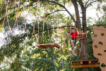 child climbs in a rope park. Boy In Adventure Park having fun in high wire park. Toddler Boy On A Ropes Course. Male toddler on zip line. Boy having a fun on Climbing Frame. Boyscout on a tree. Summer