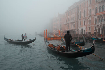 Fototapeta na wymiar Gondolier floats on the Grand Canal in foggy weather